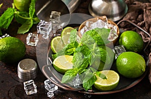 Refreshing Mojito cocktail making close-up. Mint, lime, ice ingredients and bar utensils