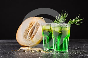 Refreshing non-alcohol drinks. Cut melon and green cocktails on a black background. Sweet drinks with liquor, lime and tarragon.