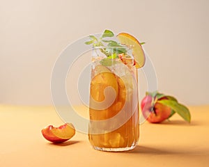 Refreshing peach ice and mint tea close up. Vegan homemade cold summer drink on tall glass on an orange background with fresh