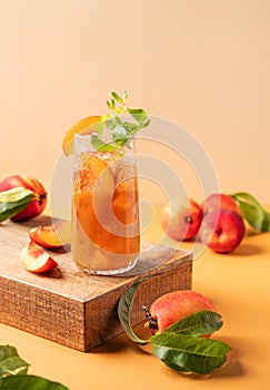 Refreshing peach ice and mint tea. Homemade cold summer drink on an orange background with fresh fruits