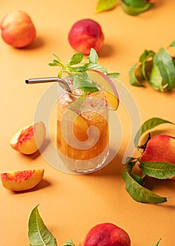 Refreshing peach ice and mint tea. Vegan homemade cold summer drink on an orange background with fresh fruits