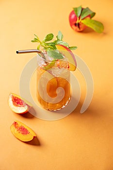 Refreshing peach ice and mint tea. Vegan homemade cold summer drink on an orange background with fresh fruits