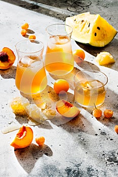 Refreshing peach ice tea or lemonade in glasses. Summer yellow fruit cocktail. Hard light harsh shadows.