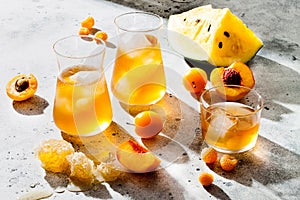 Refreshing peach ice tea or lemonade in glasses. Summer yellow fruit cocktail. Hard light harsh shadows.