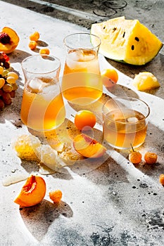 Refreshing peach ice tea or lemonade in glasses. Summer yellow fruit cocktail. Hard light harsh shadows.