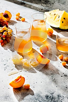 Refreshing peach ice tea or lemonade in glasses. Summer yellow fruit cocktail. Hard light harsh shadows.