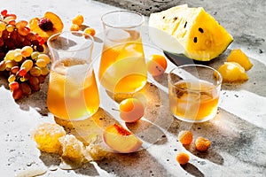 Refreshing peach ice tea or lemonade in glasses. Summer yellow fruit cocktail. Hard light harsh shadows.