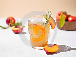 Refreshing peach tea with ice and rosemary. Homemade cold healthy vegetarian drink on a light background with fresh fruits and