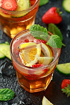 Refreshing Pimms Cocktail with Fruit and vegetables on rustic black table