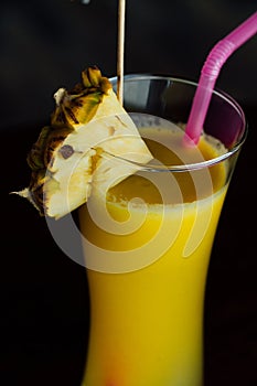 Refreshing pineapple cocktail glass with slices of pineapple, pink juice straws and decoration