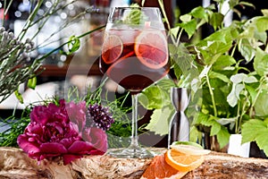 Refreshing red summer cocktail with ice, lime and mint in beautiful glass on the background of fresh flowers