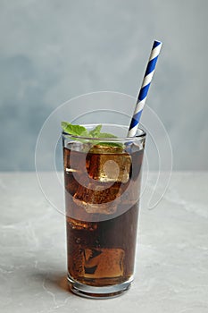 Refreshing soda drink with straw on grey table against blue background