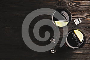 Refreshing soda drinks with ice cubes and lime on wooden table, flat lay. Space for text