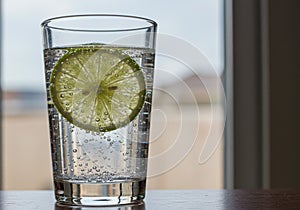 Refreshing Sparkling Water with Lime Slice by the Window