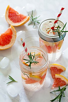 Refreshing summer drink with grapefruit and rosemary on a stone background.
