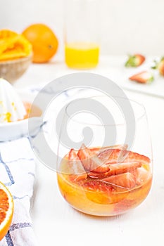 Refreshing summer drink, healthy snack - fresh strawberries with orange juice, metal basket with strawberries, oranges