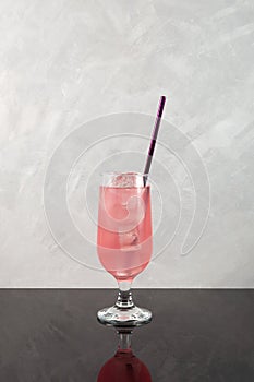 Refreshing summer iced drink. Pink cold cocktail with ice cubes in tall drinking glass