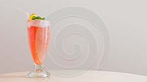 A refreshing tall glass of fresh watermelon juice served with mint, yogurt and a slice of orange