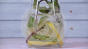 Refreshing water is poured into a glass carafe with lemon and mint