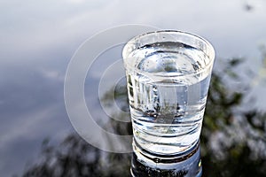 Refreshing water in transparent glass with reflection against bl