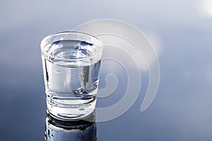 Refreshing water in transparent glass with reflection against bl