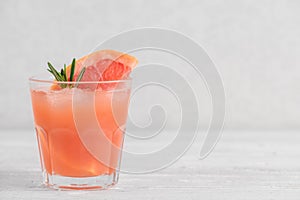 Refreshment grapefruit cocktail with rosemary and ice on white background. Healthy citrus summer drink