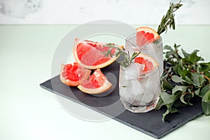 Refreshment grapefruit cocktail with rosemary on slate board. Healthy citrus summer drink, detox summer time menu