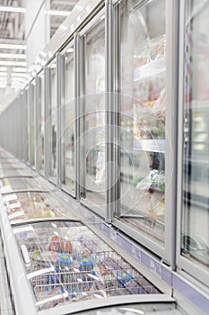 Refrigerated trucks with frozen food in a supermarket. Vertical
