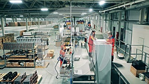 Refrigeration factory with female workers making fridges. Industrial production factory interior.