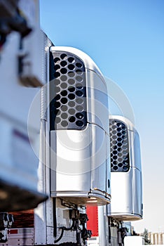 Refrigeration units on truck semi trailers stand in a row on warehouse parking lot