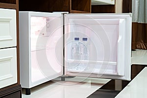 Refrigerator fridge mini size under the table counter with wooden desk beside it in hotel delux room