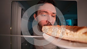 Refrigerator point of view funny hungry man opening refrigerator door and taking piece of pie at night with satisfied