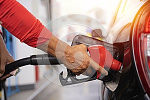 Refueling the car at a gas station fuel pump. Man driver hand refilling and pumping gasoline oil the car with fuel at he refuel