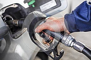 Refueling the car at a gas station fuel pump. Man hand refilling and pumping gasoline oil the car with fuel at he refuel station