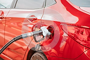 Refueling gun in the gas tank of a bright red car