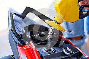 Refueling a motorbike. Close-up of a fuel nozzle inserted into a gas tank