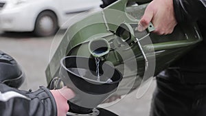 Refueling a Motorcycle, Hand pouring blue liquid into a vintage motorcycle's fuel tank, close-up with blurred