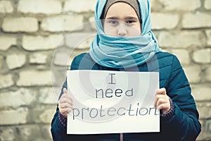 Refugee girl with an inscription on a white sheet