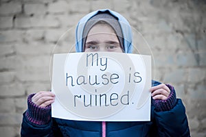 Refugee girl with an inscription on a white sheet