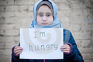 Refugee girl with an inscription on a white sheet