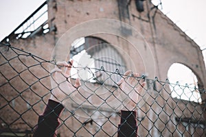 Refugee hands keeping metal fence mesh