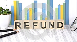 REFUND word written on the wood block with chart, glasses and pencils