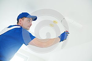 Refurbishment. Painter painting ceiling with paint roller photo