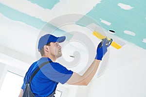 Refurbishment. Plasterer spackling a gypsum plasterboard ceiling with putty