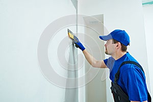 Refurbishment. Plasterer worker spackling a wall with putty