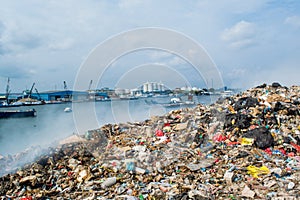 Refuse area near harbor view full of smoke, litter, plastic bottles,rubbish and trash at the Thilafushi local tropical island