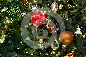 Reg, gold, green and silver christmas decorations on a christmas tree with lights