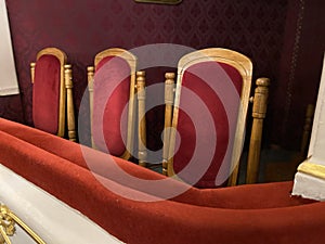 regal ornate rounded wood armed formal empty red velvet opera or movie or theatre chairs in curved row