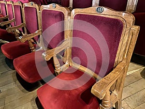 regal ornate rounded wood armed formal empty red velvet opera or movie or theatre chairs in curved row