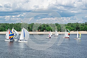 Regatta competition of lake river sailing yachts boats with sails and multicolored gennakers, reflected sky clouds in water